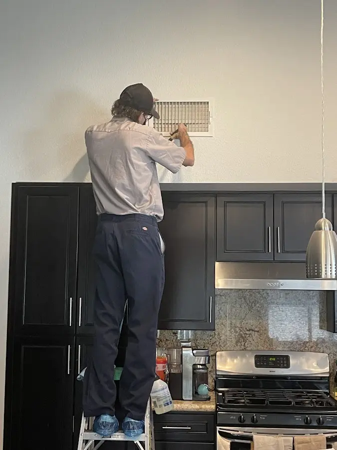 Technician inspecting an air vent during HVAC service in Conroe